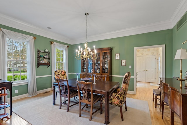dining area with visible vents, crown molding, baseboards, an inviting chandelier, and light wood-style flooring