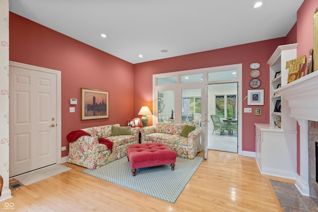 living area featuring wood-type flooring, a premium fireplace, baseboards, and recessed lighting