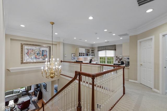 hall with a chandelier, an upstairs landing, ornamental molding, and visible vents