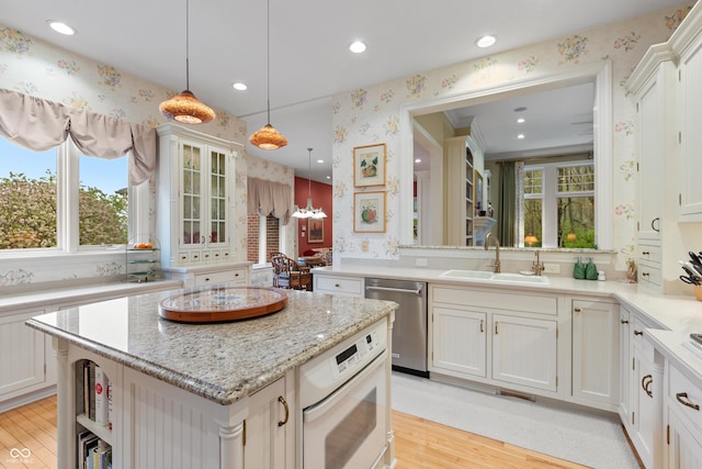 kitchen featuring a sink, dishwasher, light wood-style flooring, recessed lighting, and wallpapered walls