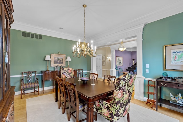 dining space featuring crown molding, light wood-style floors, ornate columns, and visible vents