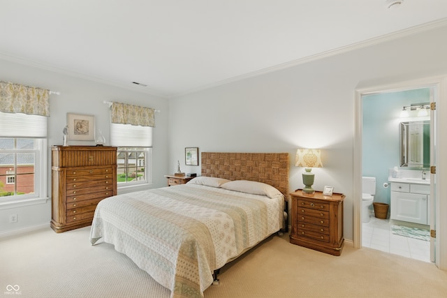 carpeted bedroom with crown molding, visible vents, baseboards, ensuite bathroom, and a sink