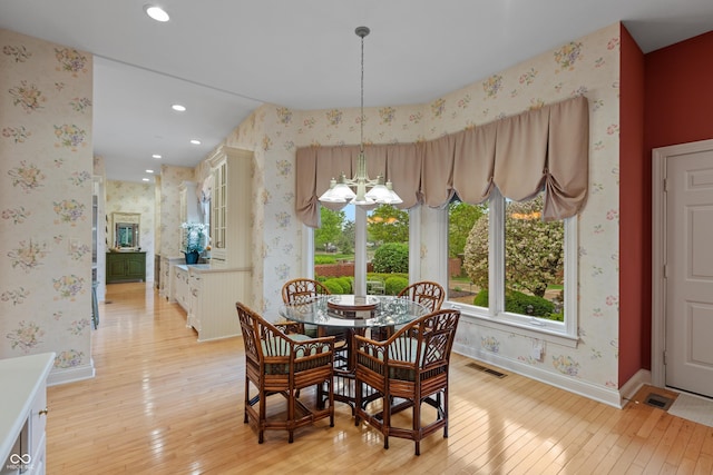 dining room with an inviting chandelier, baseboards, wallpapered walls, and light wood-style flooring