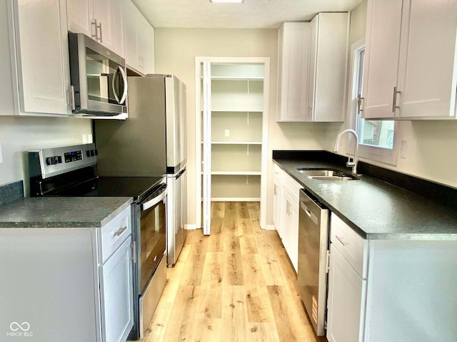 110 Renee Dr, Ellettsville, IN 47429 - kitchen with stainless steel appliances, dark countertops, light wood finished floors, and white cabinetry