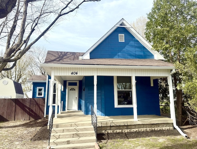 bungalow-style home featuring a shingled roof, fence, and covered porch
