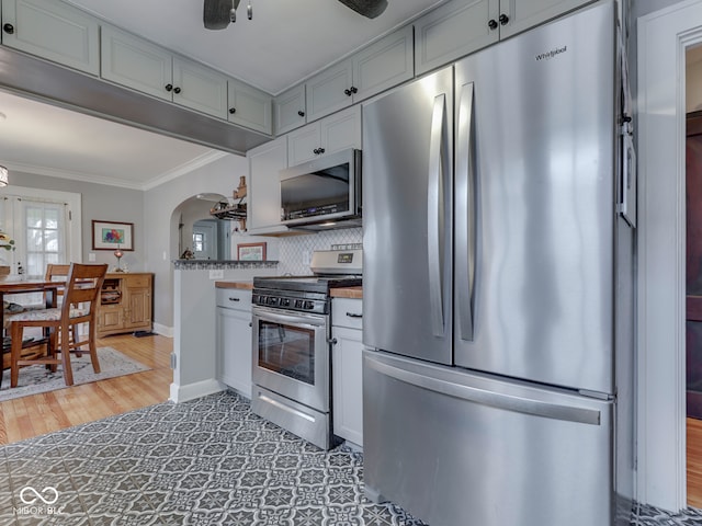 57 Worman St, Indianapolis, IN 46227 - kitchen with stainless steel appliances, backsplash, arched walkways, crown molding, and baseboards