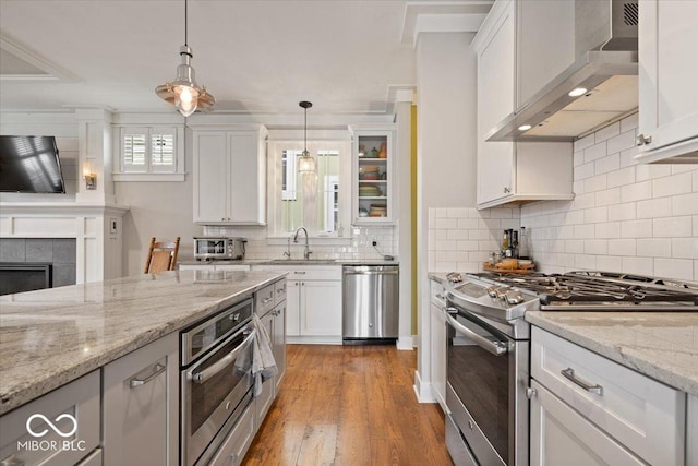 7638 Beekman Ter, Zionsville, IN 46077 - kitchen featuring stainless steel appliances, wall chimney range hood, white cabinetry, decorative light fixtures, and tasteful backsplash