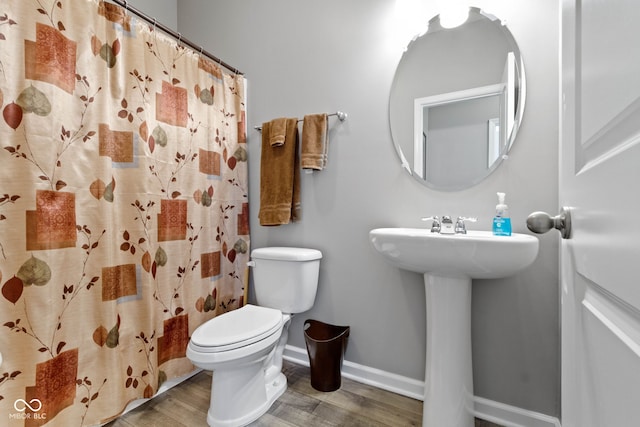 full bathroom featuring baseboards, a shower with shower curtain, wood finished floors, and toilet