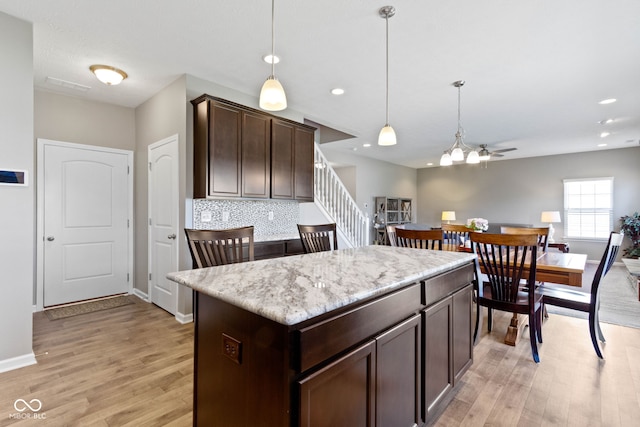 kitchen featuring decorative light fixtures, dark brown cabinetry, baseboards, and light wood-style flooring