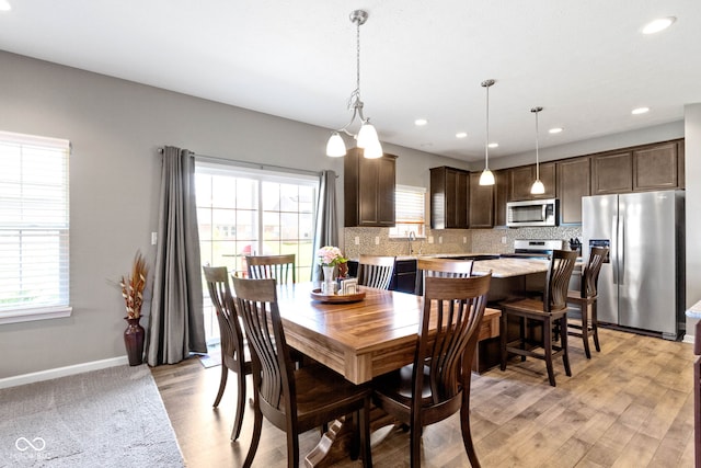 dining space with baseboards, recessed lighting, light wood-style flooring, and a healthy amount of sunlight