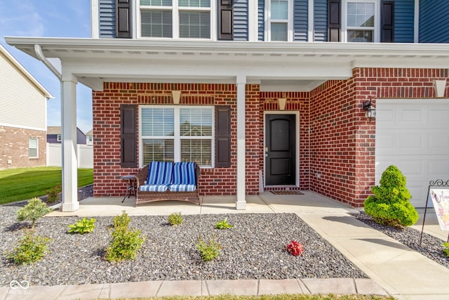 view of exterior entry featuring a porch and brick siding