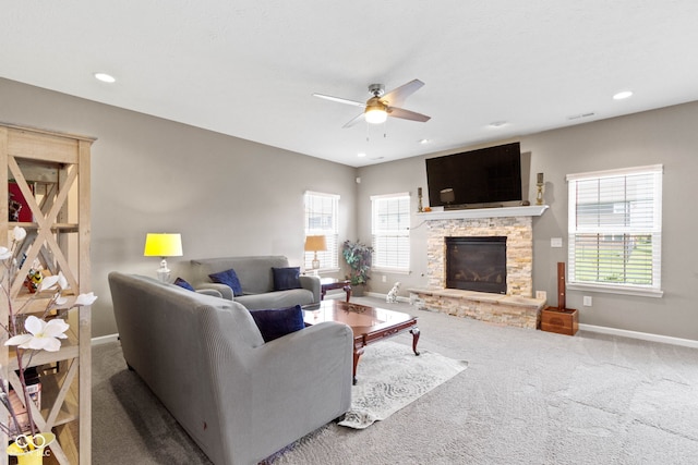 carpeted living room featuring a stone fireplace, a ceiling fan, baseboards, recessed lighting, and visible vents