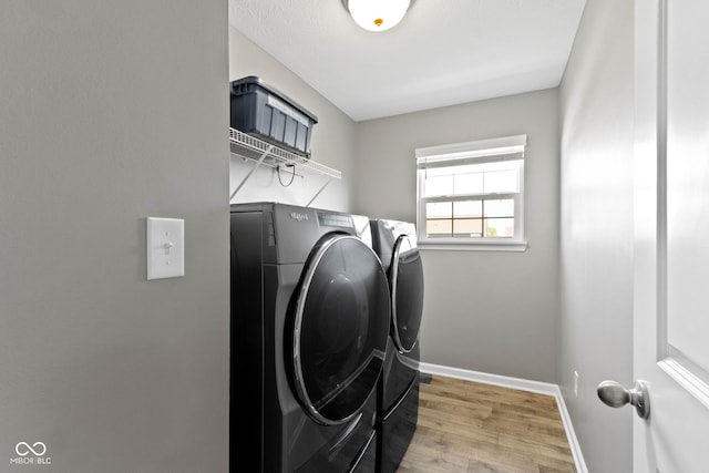 washroom featuring laundry area, washer and clothes dryer, baseboards, and wood finished floors
