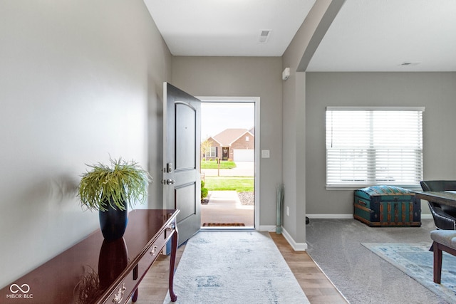entryway with arched walkways, baseboards, and wood finished floors