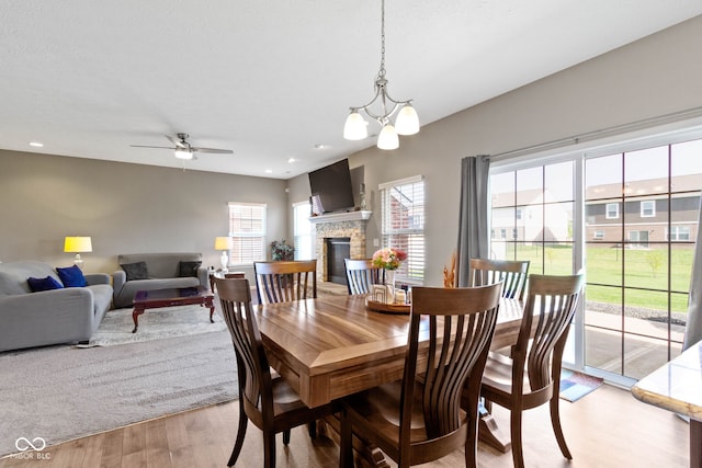 dining room featuring recessed lighting, a fireplace, ceiling fan with notable chandelier, and light wood-type flooring