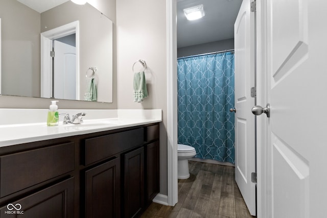 full bath featuring toilet, curtained shower, wood finished floors, and vanity
