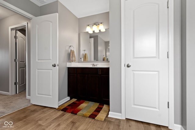 bathroom with baseboards, wood finished floors, and vanity
