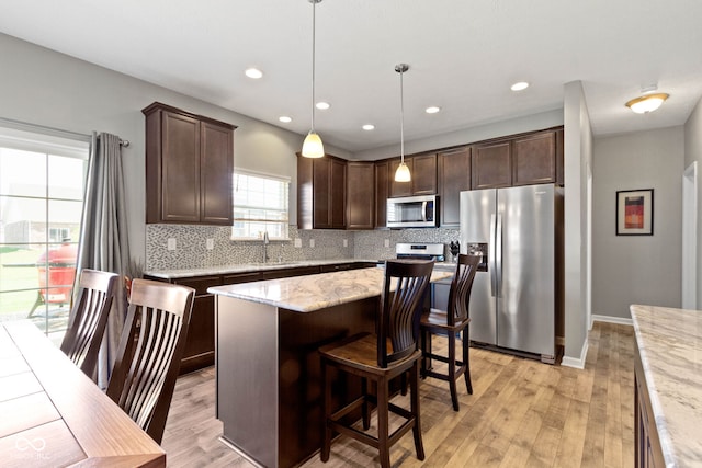 kitchen featuring light wood-style flooring, appliances with stainless steel finishes, dark brown cabinets, and tasteful backsplash