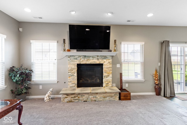 carpeted living area featuring visible vents, baseboards, and a fireplace