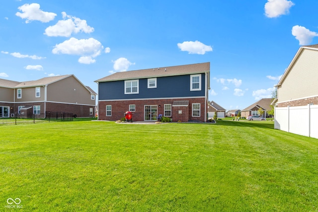 back of property featuring brick siding, fence, and a yard