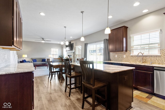 kitchen with ceiling fan, a sink, open floor plan, tasteful backsplash, and stainless steel dishwasher