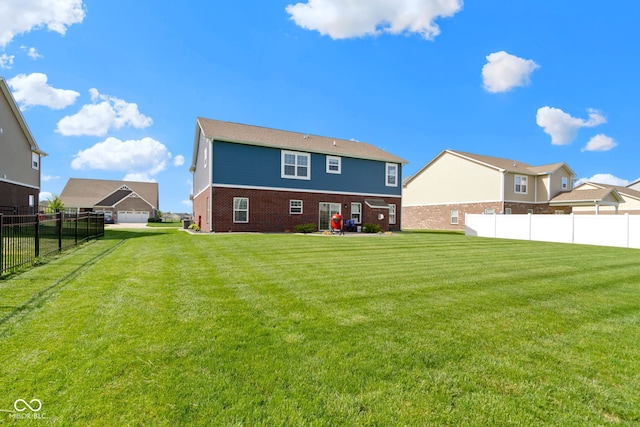 rear view of property featuring a yard, brick siding, and fence