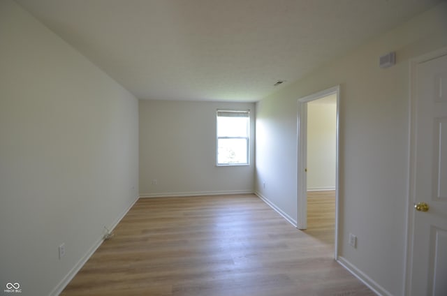 unfurnished room with baseboards, light wood finished floors, and visible vents