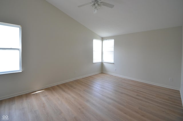 unfurnished room with light wood-type flooring, baseboards, ceiling fan, and vaulted ceiling