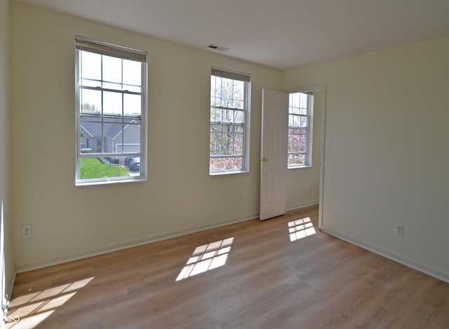 unfurnished room with visible vents, wood finished floors, and baseboards