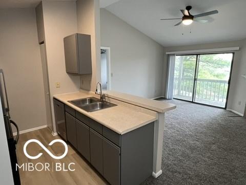 4311 Village Parkway Cir W Unit 6, Indianapolis, IN 46254 - kitchen with a peninsula, a sink, open floor plan, baseboards, and black dishwasher