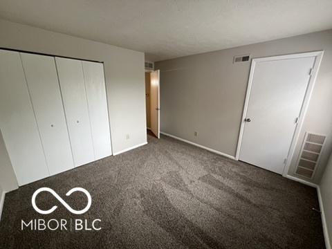 4311 Village Parkway Cir W Unit 6, Indianapolis, IN 46254 - unfurnished bedroom with baseboards, visible vents, carpet, and a closet