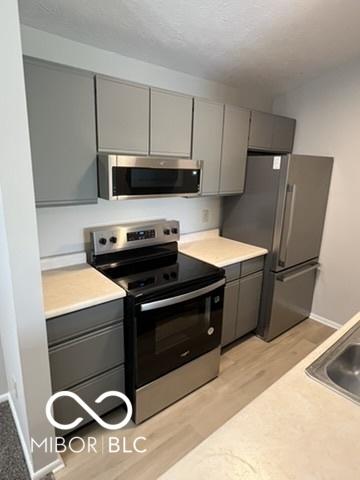 4311 Village Parkway Cir W Unit 6, Indianapolis, IN 46254 - kitchen featuring appliances with stainless steel finishes, gray cabinetry, and light wood-style flooring