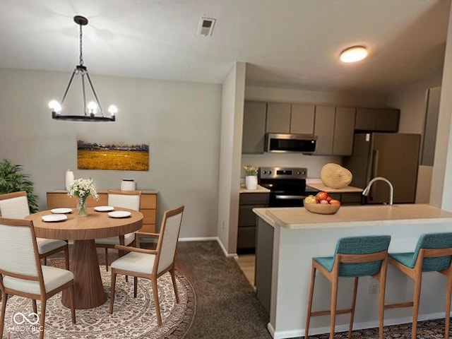 4311 Village Parkway Cir W Unit 6, Indianapolis, IN 46254 - kitchen with gray cabinets, pendant lighting, stainless steel appliances, light countertops, and a kitchen bar
