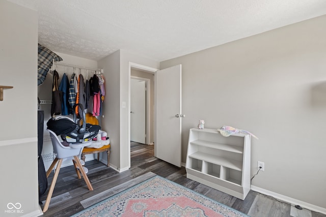 bedroom featuring baseboards, wood finished floors, and a textured ceiling