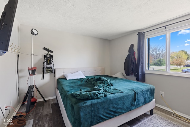 bedroom with baseboards, wood finished floors, and a textured ceiling