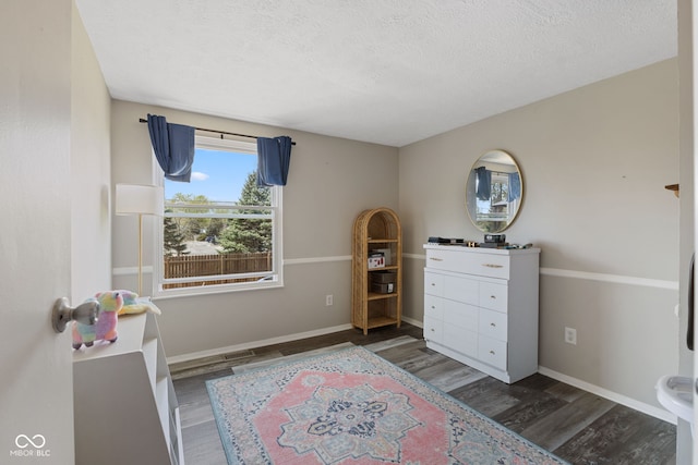 bedroom with wood finished floors, a textured ceiling, and baseboards