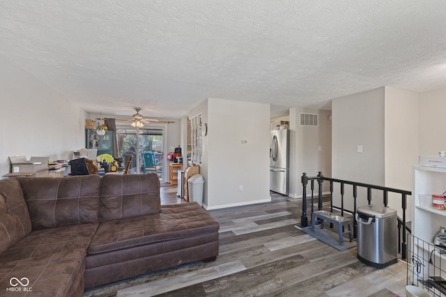 living room featuring a ceiling fan, wood finished floors, a textured ceiling, baseboards, and visible vents
