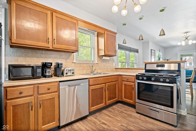kitchen with stainless steel appliances, a sink, a chandelier, and a peninsula