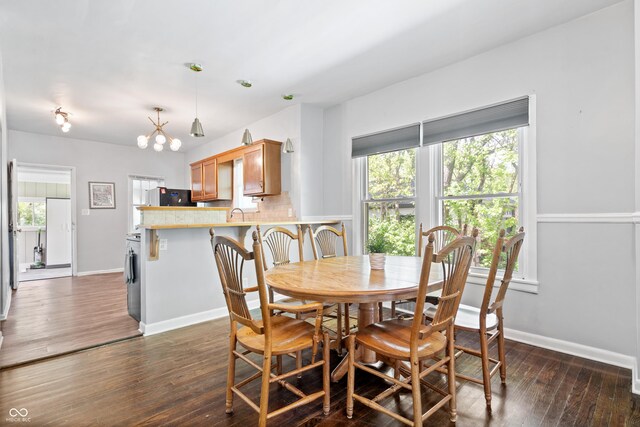 dining space featuring dark wood-style floors, baseboards, and a chandelier