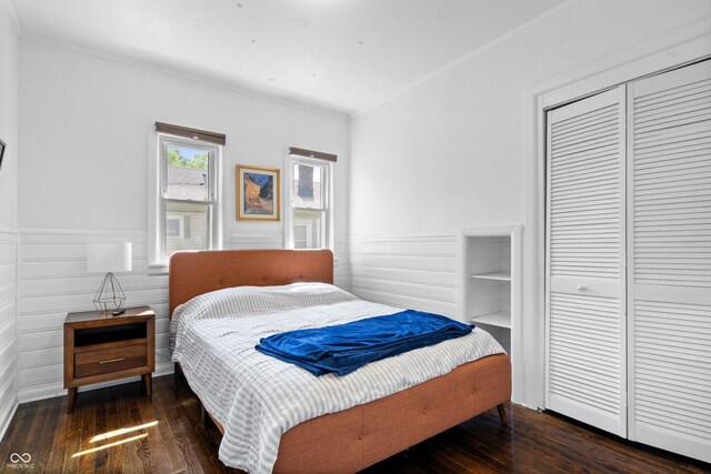 bedroom with crown molding, a closet, hardwood / wood-style floors, and a wainscoted wall