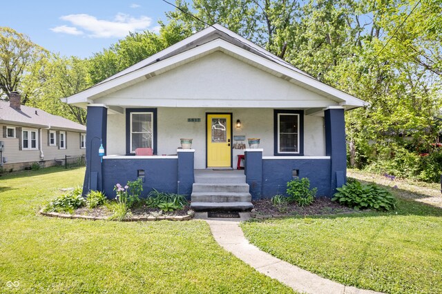 bungalow-style house featuring stucco siding, a porch, and a front yard