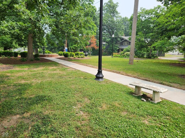 view of community with a yard and view of wooded area