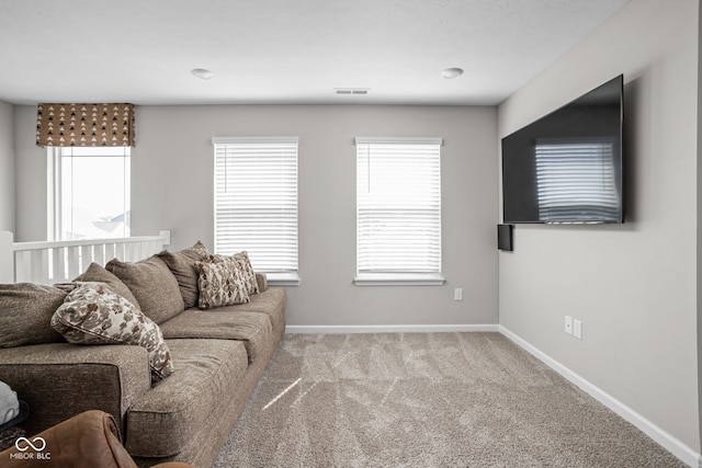 carpeted living room featuring baseboards, visible vents, and a wealth of natural light