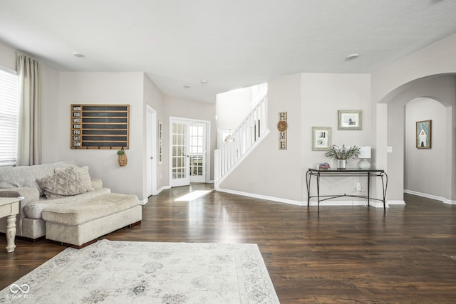 living area featuring stairway, baseboards, arched walkways, and wood finished floors