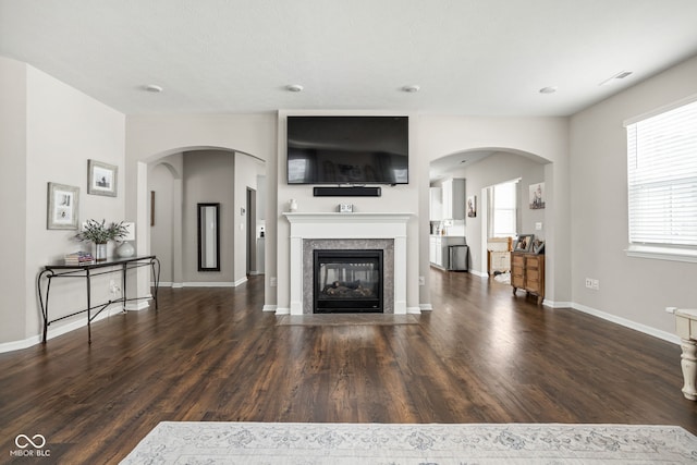unfurnished living room featuring a healthy amount of sunlight, baseboards, a tiled fireplace, and wood finished floors