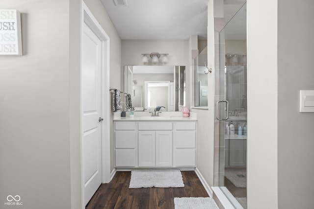 bathroom featuring a shower stall, wood finished floors, and vanity
