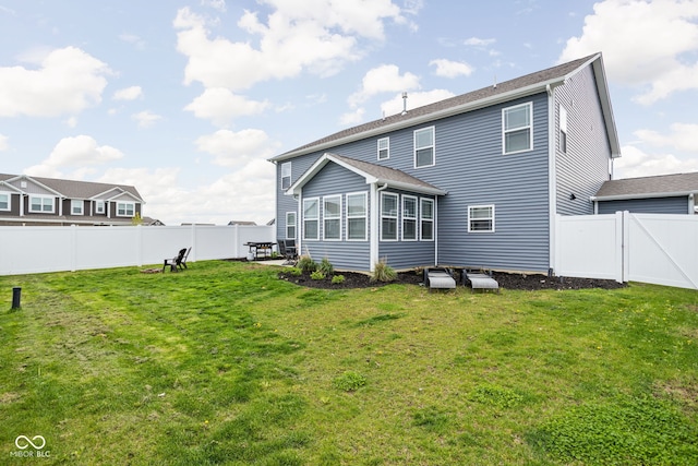 rear view of property featuring a fenced backyard, a sunroom, and a lawn