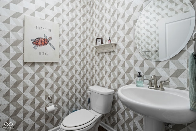 bathroom featuring a sink, tile walls, and toilet