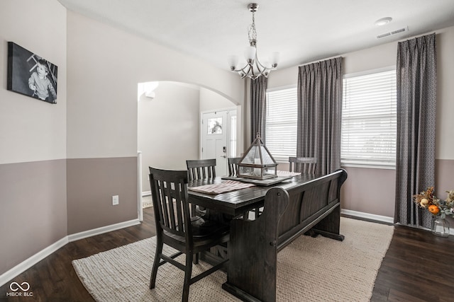 dining area with arched walkways, baseboards, a notable chandelier, and visible vents