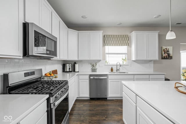 kitchen featuring a sink, dark wood finished floors, appliances with stainless steel finishes, and tasteful backsplash